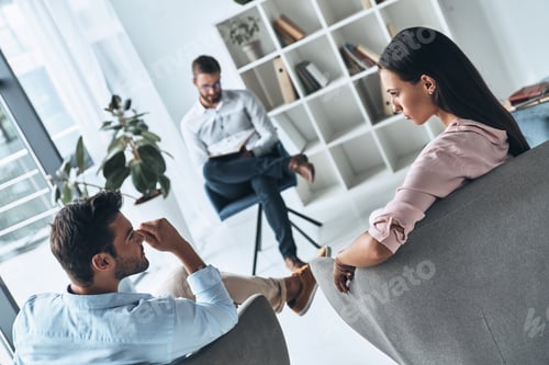 Preview: Helping others. Young married couple talking while sitting on the therapy session with psychologist