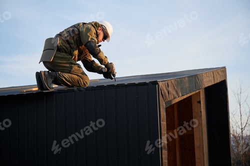 Preview: Builder installing corrugated iron sheet used as facade of future wooden frame house.