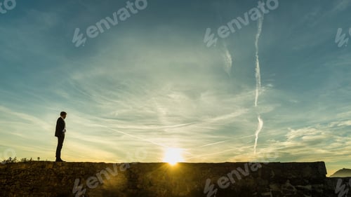 Preview: Businessman standing facing the rising sun