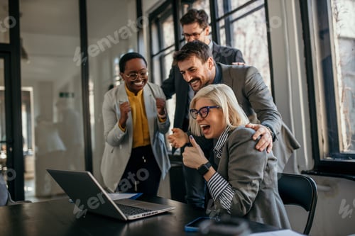 Preview: Excited business team celebrating success at work with laptop