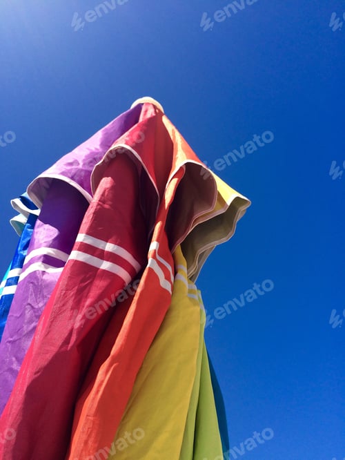 Preview: Colorful beach umbrella on a summer blue sky background.