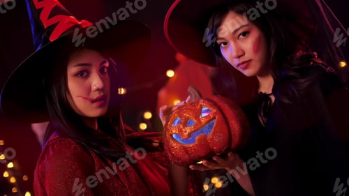 Preview: Two young women in witch costumes having fun at Halloween party.