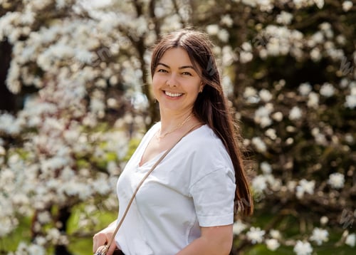 Preview: Portrait of beautiful smiling girl in blooming spring park outdoors.