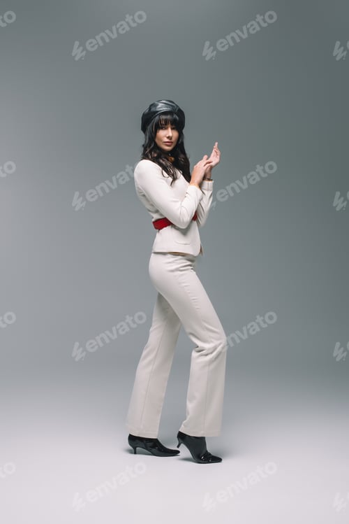 Preview: attractive brunette woman in white suit standing on gray