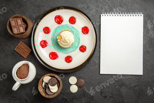 Preview: top view sweets on the table an appetizing cupcake with sauces next to the white notebook and bowls