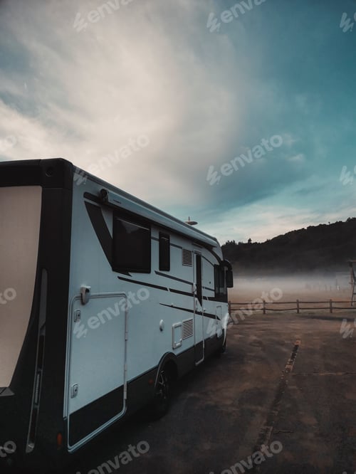 Preview: Rv vehicle camper van parked in the nature with fog and beautiful blue sky in background