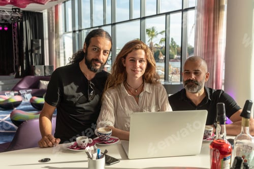 Preview: Group of three entrepreneurs using laptop and having coffee in office
