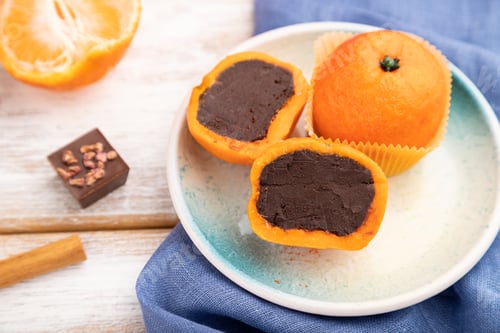 Preview: Truffle chocolate tangerine candies on a white wooden background. Side view, selective focus.