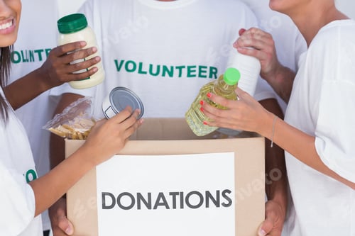 Preview: Group Of Volunteers Putting Food In Donation Box