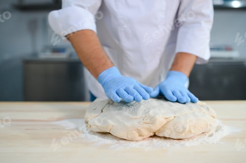 Preview: A male cook is mixing the dough in the kitchen. Production of various semi-finished products