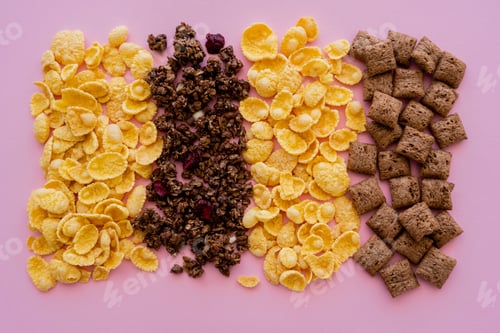 Preview: top view of assorted breakfast cereal corn flakes with puffs and granola isolated on pink