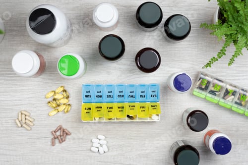 Preview: Overhead view of a weekly pill organizer and a variety of pills, capsules and tablets