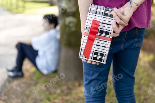 Preview: Man hiding gift for his boyfriend celebrating anniversary in a park