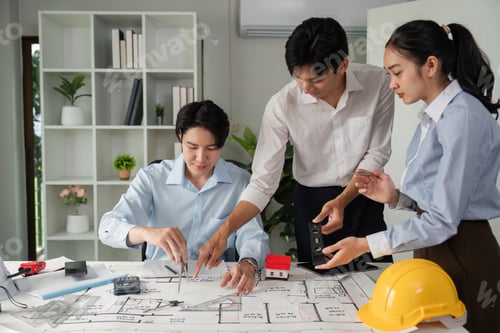 Preview: A team evaluates project details with models and blueprints on the table.