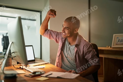 Preview: Cropped shot of a young designer doing a fist pump while working late in an office