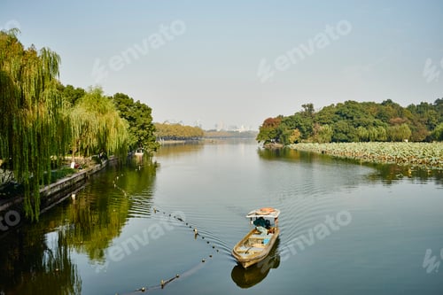 Preview: A serene moment on a quiet river with a lone boat amidst lush greenery.