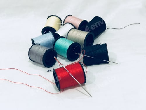 Preview: Colorful Thread Spools with Needles on White Background