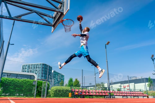 Preview: Tall guy basketball player jumps to the hoop with the ball in his hand to score a spectacular dunk
