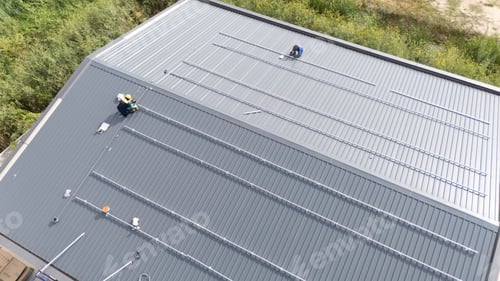 Preview: Workers installing solar panels on a building roof in a sunny location