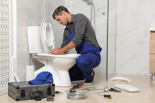 Preview: Professional plumber working with toilet bowl in bathroom