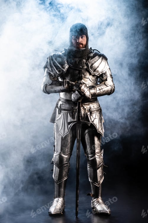 Preview: handsome knight in armor looking at camera and holding sword on black background