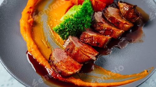 Preview: Closeup shot of a gourmet dish with sliced steak and sauce on a table