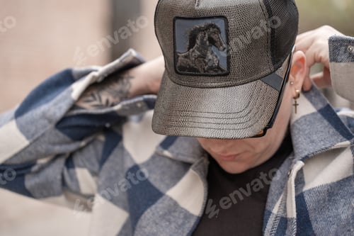 Preview: Urban Fashion with Edge: Blurred-Face Individual in Checkered Jacket and Horse Patch Cap