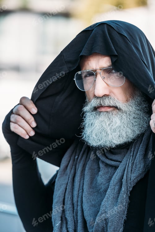 Preview: senior bearded man in fashionable clothing and eyeglasses posing on street