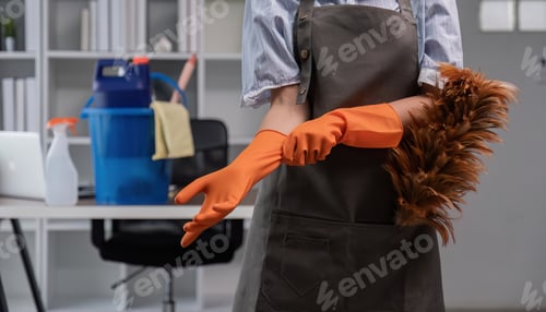 Preview: close up, A young cleaning lady is wearing glove and preparing to clean the office. Young housewife