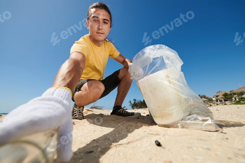 Preview: Man Cleaning Sandy Beach With Trash Bag