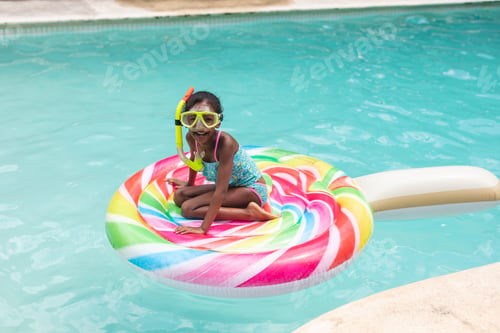 Preview: Portrait of happy african american girl with snorkel sitting on inflatable ring in swimming pool