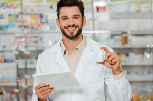 Preview: Pharmacist smiling at camera while holding pills and digital tablet in apothecary