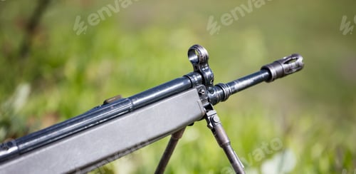Preview: Shotgun on easel. Front side of weapon with close up view on blurred nature background.