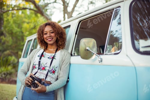 Preview: Woman leaning on campervan with camera