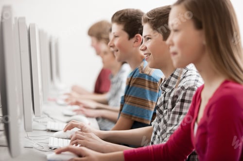 Preview: A group of young people, boys and girls, students in a computer class working at screens.