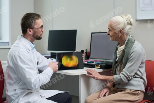 Preview: Male Doctor Showing Senior Woman Eye Scan on Tablet