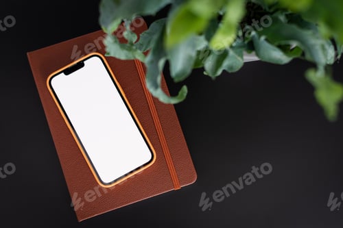 Preview: Mobile phone with a diary on a black desk.