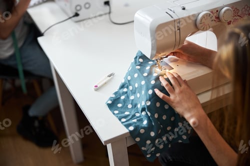 Preview: Little seamstress using sewing machine in workshop