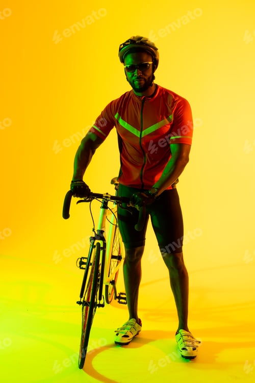 Preview: Vertical image of african american male cyclist looking at camera in yellow lighting