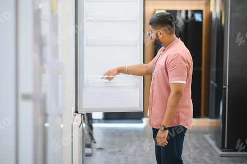 Preview: Smart modern indian male customer choosing large fridges in domestic appliances section