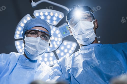 Preview: Adult caucasian surgeon working with assistant in operating room.