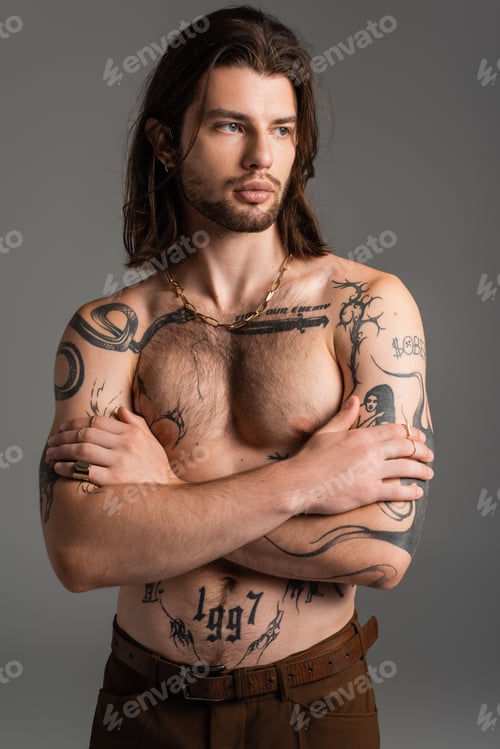 Preview: Muscular and tattooed model crossing arms isolated on grey