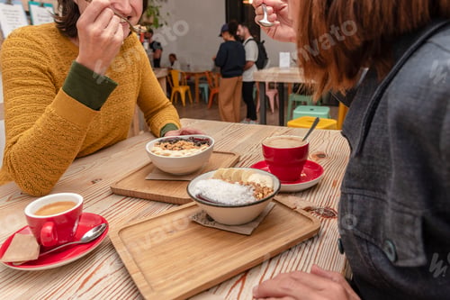 Preview: Two friends having some acai smoothie bowls and coffe for breakfast