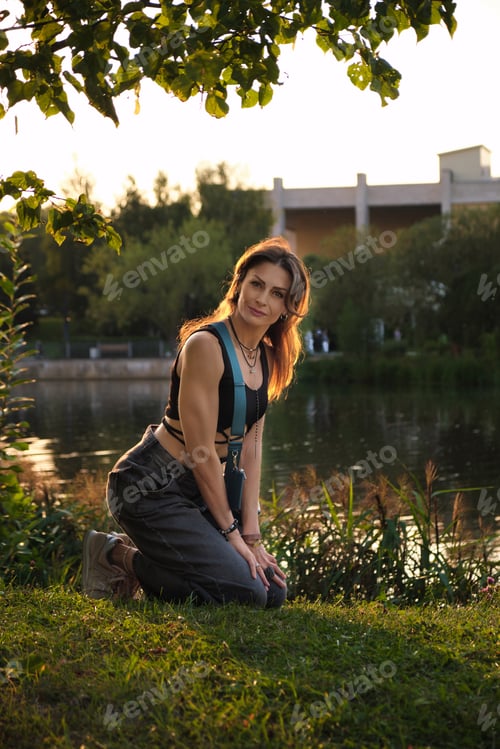 Preview: A woman kneels by the water's edge, her windswept hair and soft expression conveying a balance of