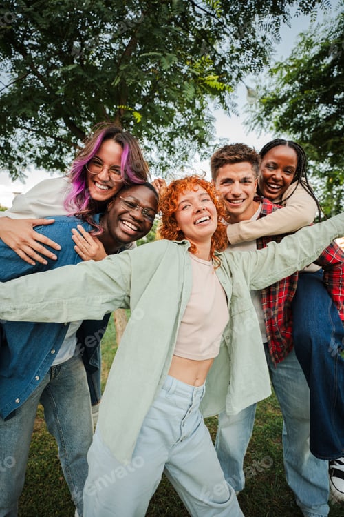 Preview: Vertical. Group of joyful young friends having fun outdoors, embracing and laughing together in a