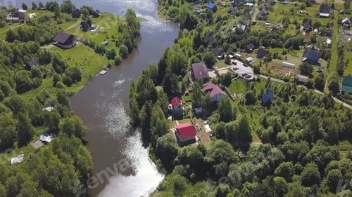 Preview: Aerial view of a town with many green trees located along the river in a sunny summer day. Clip