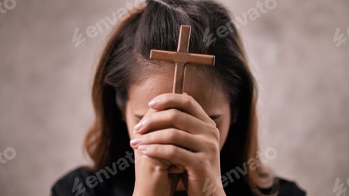 Preview: A young Asian Christian woman praying to Jesus Christ in a church.