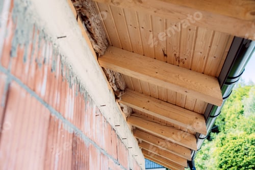 Preview: Wooden roof structure showing insulation material being installed on brick wall