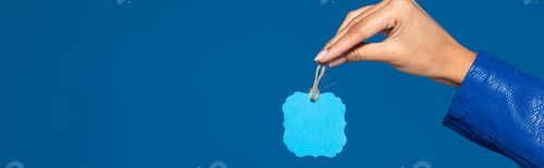 Preview: cropped view of african american woman holding blank label isolated on blue, panoramic shot