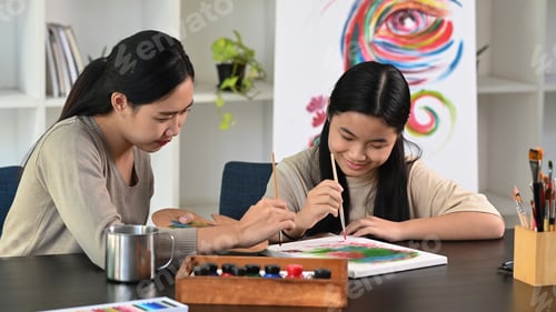 Preview: Happy asian girl painting picture with teacher at art class.